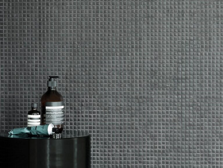 Donker Piet Boon TINY CONCRETE mozaïek op een wand met badkamerflesjes