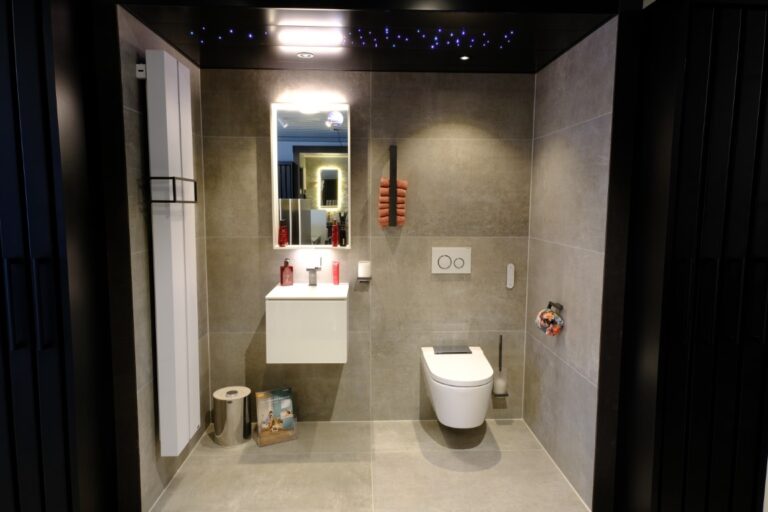 Toiletruimte met grijze tegels en verlichte spiegel in de showroom van Brinkman Stitselaar
