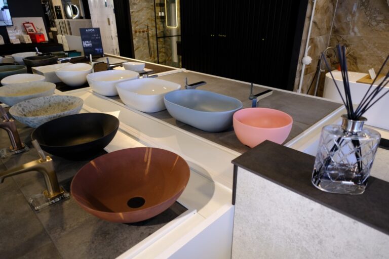 Gekleurde waskommen naast elkaar op een presentatiewand in de showroom