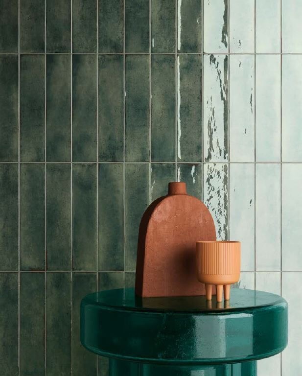 Groene glanzende wandtegels achter een groene bijzettafel